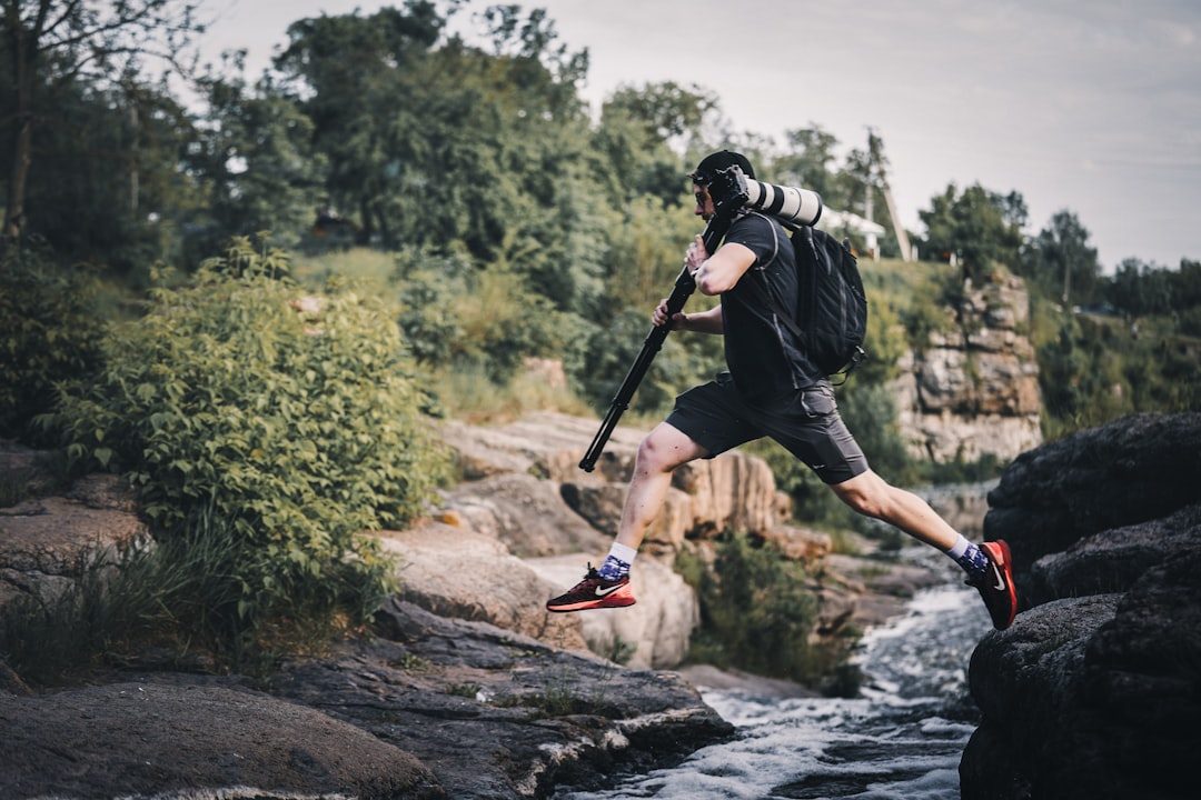 a man with a baseball bat jumping over a river