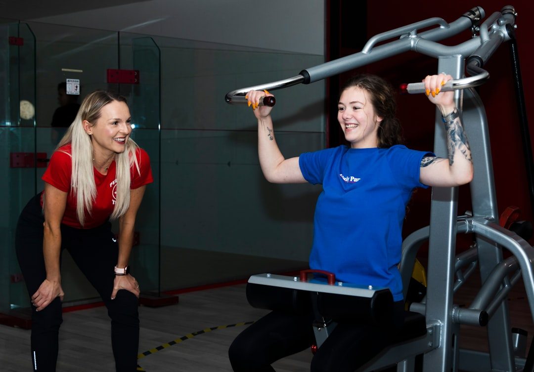 woman in blue crew neck t-shirt sitting on black and gray exercise equipment