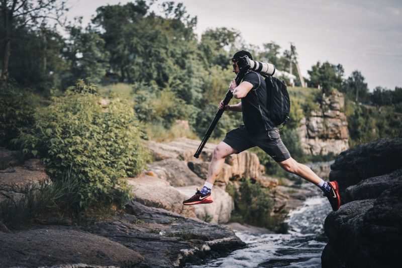 a man with a baseball bat jumping over a river