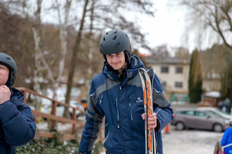 Young man holding skis and wearing a helmet