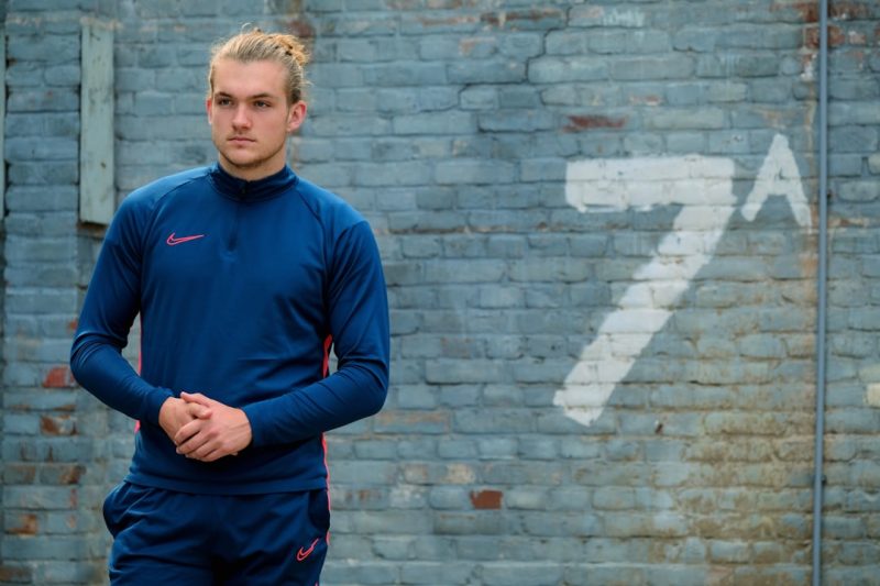 a man standing in front of a brick wall