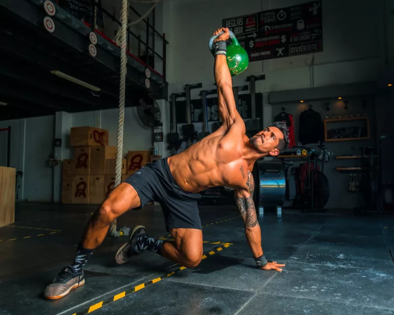 Athlet/in führt die Übung Kettlebell Overhead Lunge aus